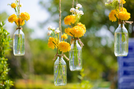 Yellow flowers in vintage bottles hanging from trees