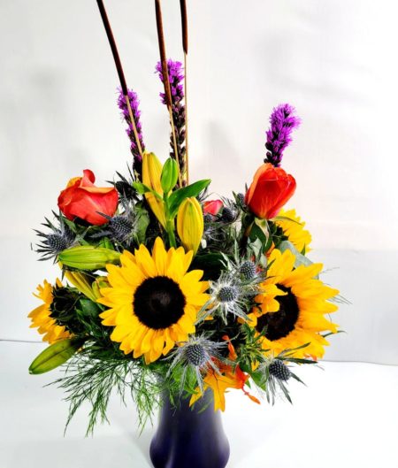 Thankful that Fall is finally here? Send a bouquet to share your thanks! Sunflowers, purple liatris, orange lilies, eryngium, fall leaves and a beautiful cobalt blue vase.  We want you to have the best so we may sub products of equal or greater value if a product is unavailable. Please understand substitutions may be made. If you have questions about this please call our shop directly.